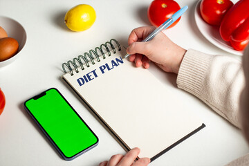 Weight loss diet planning concept. Flat lay of vegetables and notebook. Woman hands writing down...