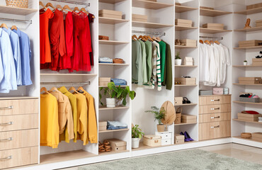 Big wardrobe with different stylish clothes and accessories in dressing room
