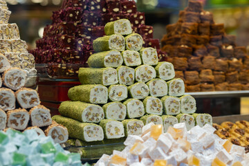 A colorful assortment of Turkish delights, nougat, and pistachio rolls stacked in a vibrant market stall showcase.