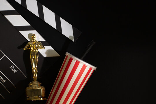 Oscar statue with clapperboard and soda cup on black background, golden statuette of Hollywood, recognition of movie stars, prize for cinematic success,Moscow, Russia, January 21, 2025