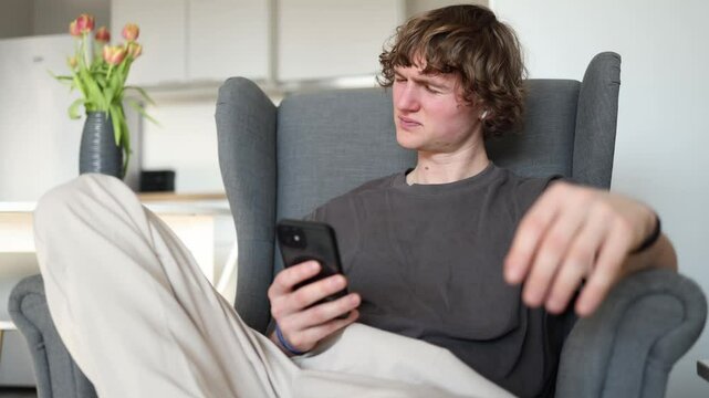 Disappointed but takes it easily A young man looks at his phone with a subtle frown, showing slight frustration but calmly accepting the situation, unfazed by whatever he has seen on the screen.