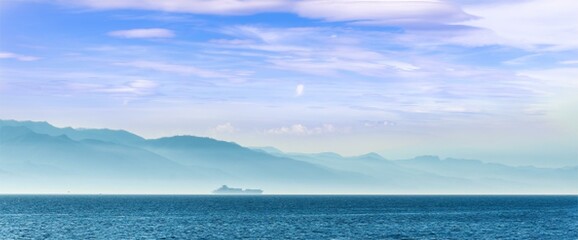tropical seascape of sailing kargo tanker ship in sea with beautiful sunset and mountains on...