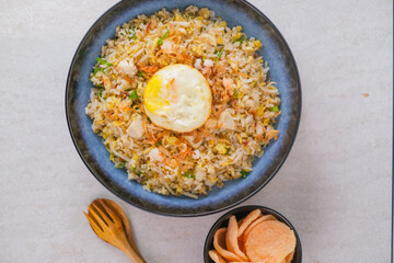 Flavorful Indonesian, Kampung Fried Rice Served With Fried Egg, Fresh Vegetables, Fried Shallots, And Crackers For A Traditional Culinary Experience.