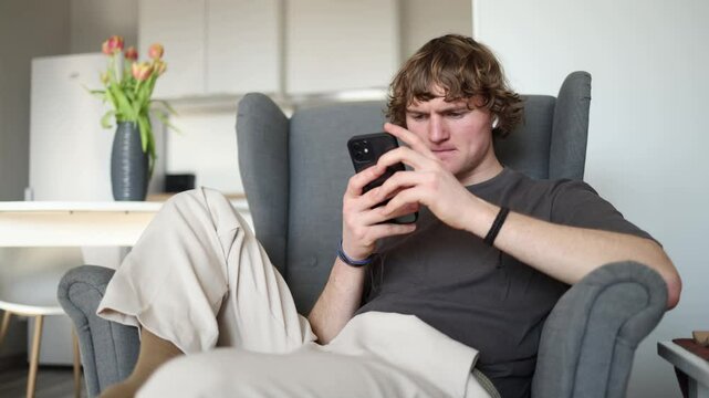 Looking lost and unsure of what to do, the young man stares at his phone, seemingly struggling with a decision or trying to figure out what to do next.