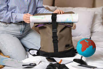 Female traveler packing backpack in bedroom, closeup. Itinerary concept