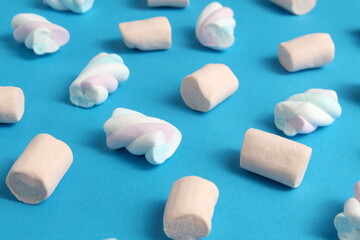 Texture of marshmallows of different colors scattered on a blue background.	