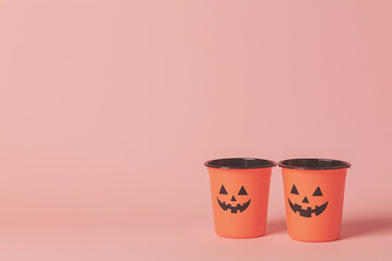 Jack O' Lantern Cups: Two festive orange cups, adorned with carved pumpkin faces, stand against a serene backdrop, evoking the spirit of the Halloween season.