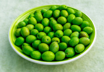 Beautiful kitchen plate with fresh green olives on monochrome green salad background. Olive dish closeup, foor and drink concept