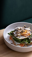 Bowl of waffles and salmon with egg and seeds on cafe table