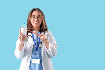 Female doctor with bottle of water on blue background