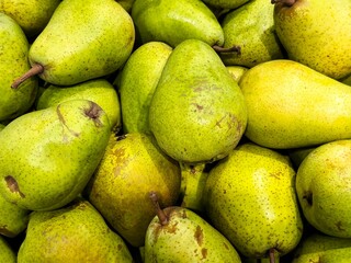 Fresh green pears stacked neatly in a market during the daytime