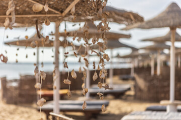 Seashells hanging from straw umbrellas creating relaxing beach atmosphere in marsa alam, egypt