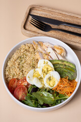 Plate with meat, eggs, vegetables and couscous on beige background angle view