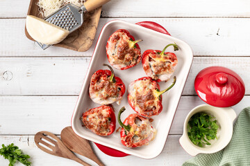 Stuffed peppers with Turkey mince under a cheese crust and green lettuce leaves, top view.