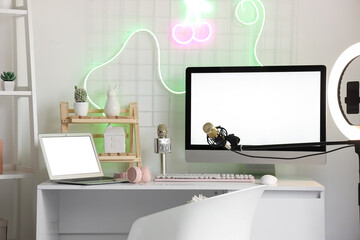 Blogger's workplace with blank computer monitor and laptop in office