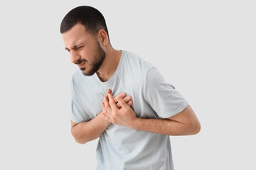 Young man suffering from chest pain on white background