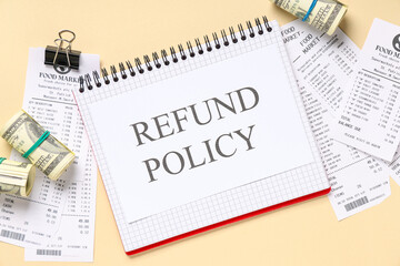 Notebook with text REFUND POLICY, receipts from food market and money on beige background