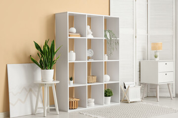 Interior of living room with white shelf unit, folding screen and table