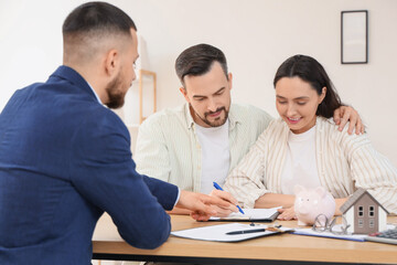 Young couple with real estate agent filling out house rental agreement in office