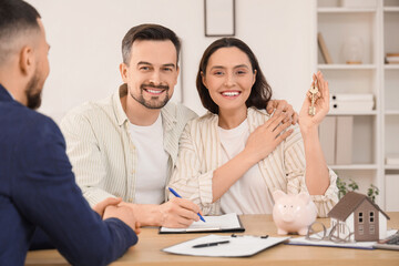 Young couple with real estate agent filling out house rental agreement in office
