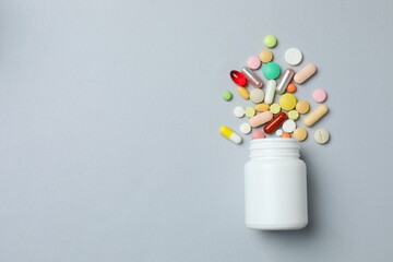 White bottle with pills on gray background, top view
