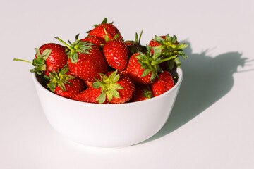 Big red ripe delicious strawberries in a deep dish on a white table. White background.	