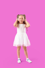 Cute little girl in headphones on violet background