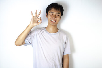 Asian teenager in white t-shirt is posing "OKAY" with a smile