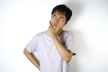 Asian teenager in white t-shirt is posing in surprise with hand on chin
