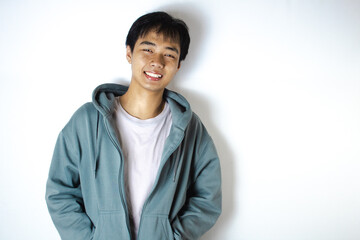 Asian teenager in white t-shirt and blue hoodie, smiling sweetly