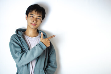 Asian teenager in white t-shirt and blue hoodie, posing with two fingers and a slight smile