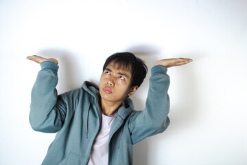 Asian teenager in white t-shirt and blue hoodie, posing holding weight from above