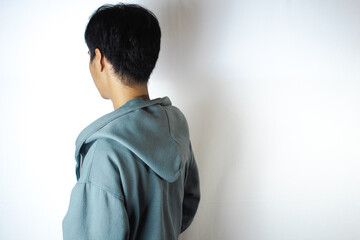 Asian teenager in white t-shirt and blue hoodie, posing facing back