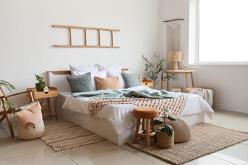 Interior of light bedroom with big bed and tables