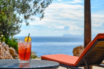 Cocktail on a table overlooking the ocean from a lounge chair in a sunny location
