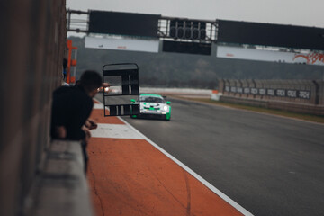 A member of the racing team displays a timing board to the driver on the track during the race