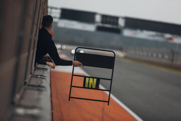 A member of the racing team displays a timing board to the driver on the track during the race