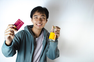 Asian teenager in white t-shirt and blue hoodie, posing attractively showing his credit card and drinking glass