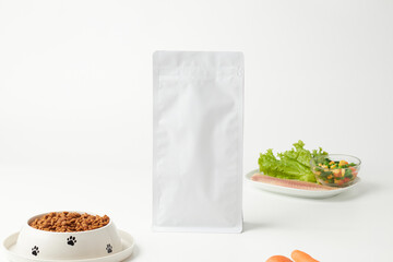 Dog Food Packaging Next to a Bowl of Kibble and Fresh Vegetables on a Clean White Background