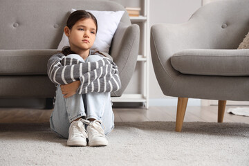 Sad girl sitting on floor at home. Adoption concept