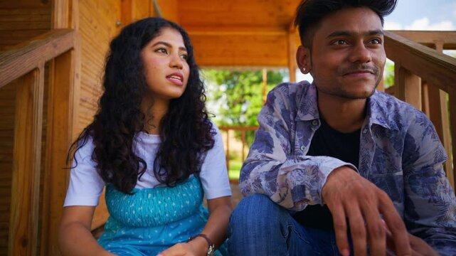 Couple sits on wooden porch talking leisurely