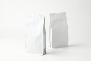 Two White Packaging Bags Standing Upright on a Light Background, Ready for Product Display or Shipping Purposes