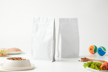 Two White Bags of Pet Food Placed on a Table With Assorted Pet Items and Fresh Ingredients