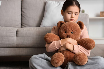Sad girl with toy bear sitting at home. Adoption concept