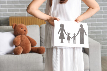 Cute girl with paper family figure at home, back view. Adoption concept