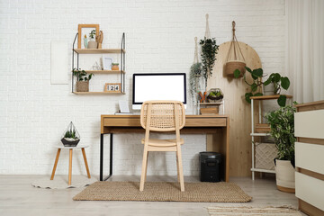 Fototapeta premium Comfortable workspace with modern computer and houseplants near white brick wall