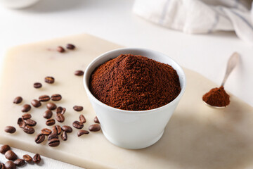 Bowl of coffee powder with beans and spoon on white background