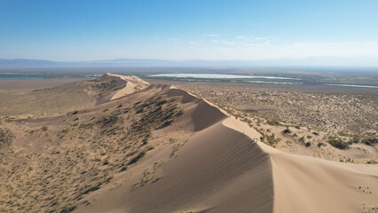 Tourists are hiking along the crest of the singing barkhan, a giant sand dune in altyn-emel national park, known for emitting a low-pitched humming sound in dry weather