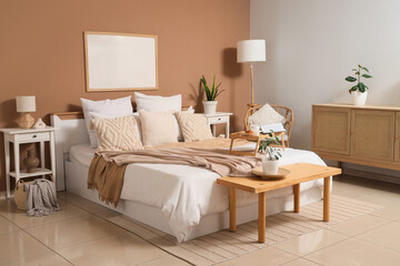 Interior of cozy bedroom with big bed, wooden bench and tables