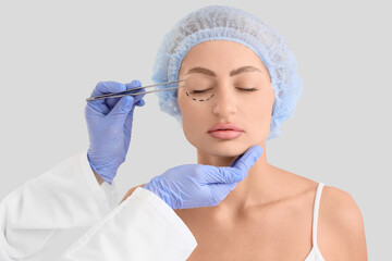 Young woman and plastic surgeon with tool on light background, closeup. Blepharoplasty concept